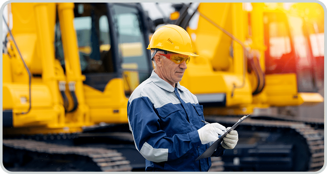 Employee in front of construction vehicles