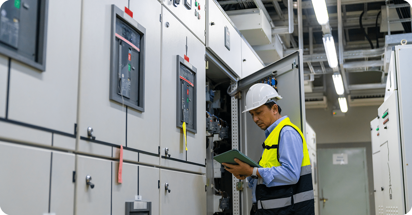 Professional engineer in safety uniform working at factory server electric control panel room.